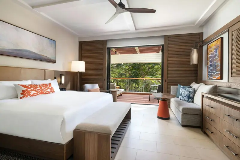 Une chambre lumineuse avec un grand lit et un coin salon donnant sur une terrasse.