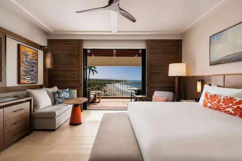 Une chambre lumineuse avec un lit et un espace salon donnant sur une vue sur la mer.