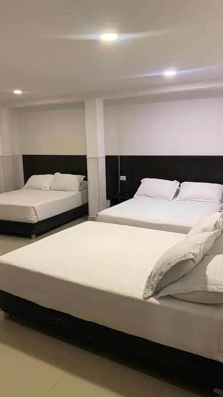 Une chambre avec deux lits simples et un lit double.