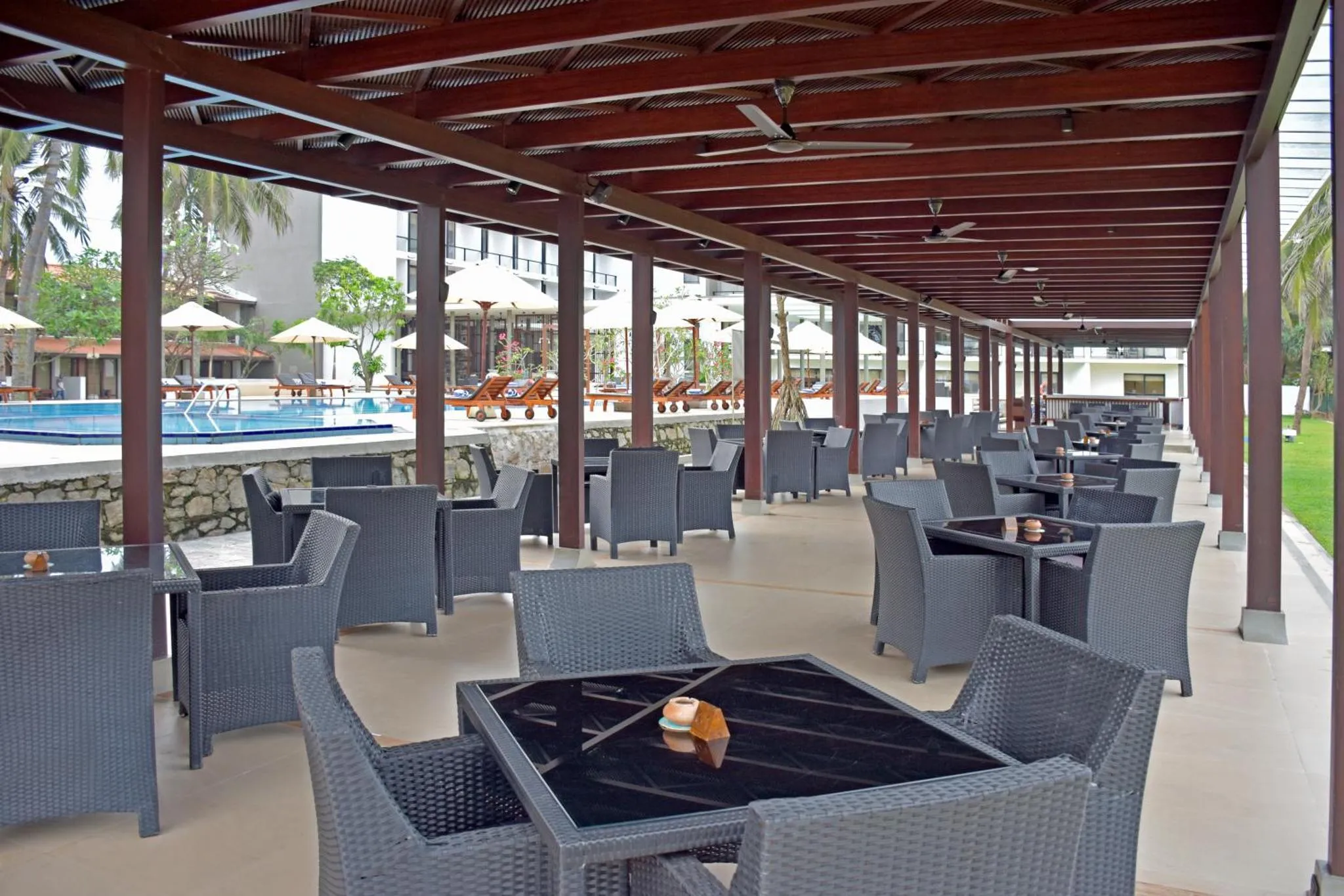 Terrasse ombragée avec tables et chaises pour les repas.