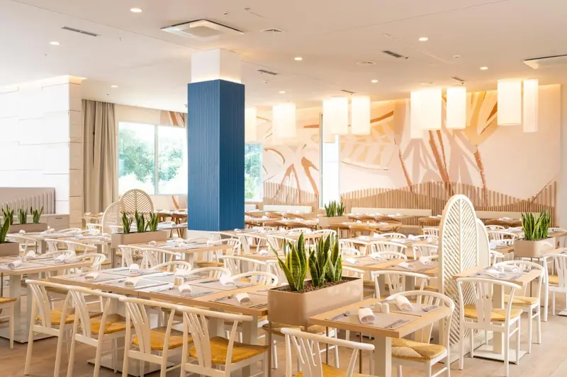 Une salle lumineuse avec de nombreuses tables dressées pour un repas.