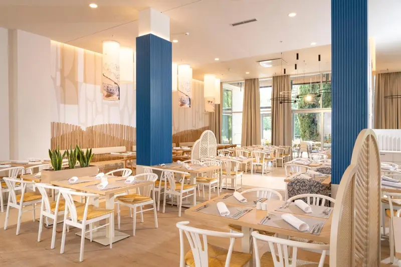 Une salle lumineuse avec des tables dressées pour le repas.