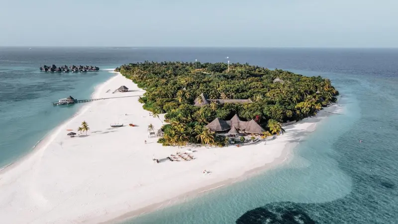 Vue aérienne d'une île tropicale avec une plage de sable blanc et une végétation luxuriante.
