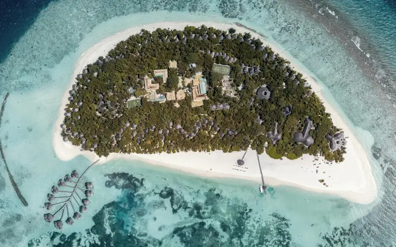 Vue aérienne d'une île tropicale bordée de plages et de végétation luxuriante.