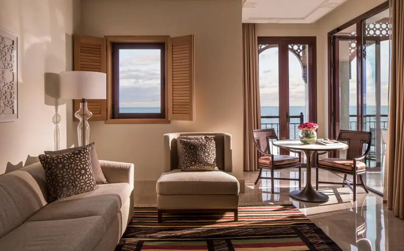 Un salon lumineux avec canapé, fauteuils et table basse donne sur une vue mer.