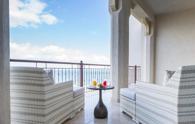 Deux fauteuils en osier sur une terrasse avec une table basse et des boissons.