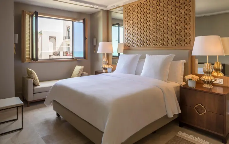 Une chambre lumineuse avec un grand lit recouvert de draps blancs et des tables de chevet.