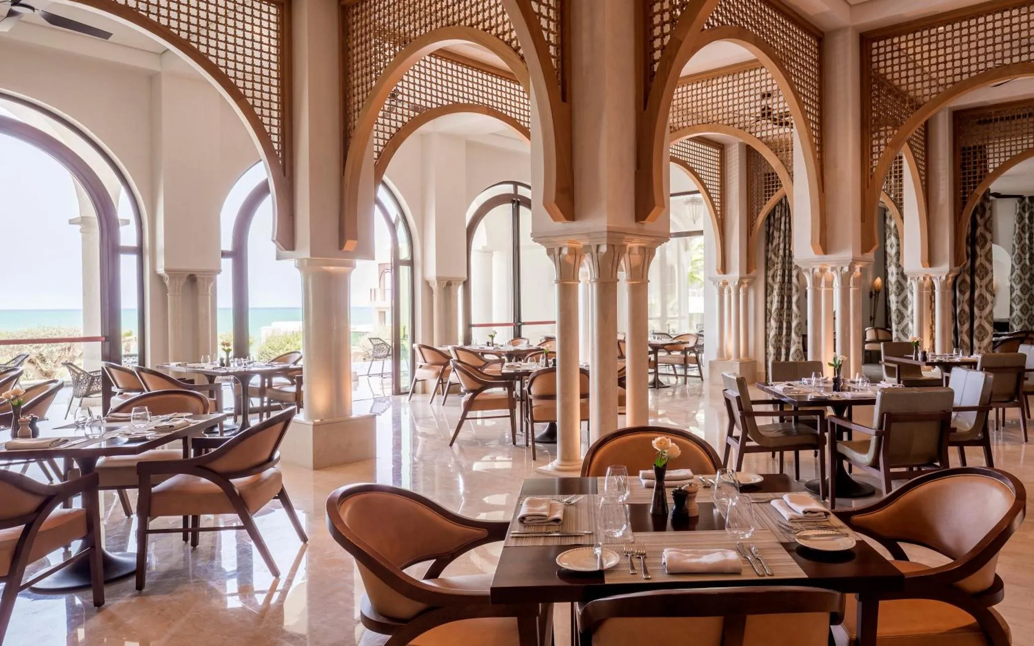 Une salle de restaurant lumineuse avec des tables dressées et des arches décoratives.