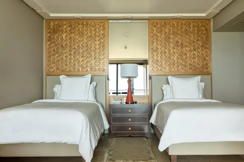 Une chambre avec deux lits simples et une décoration en bois tressé.