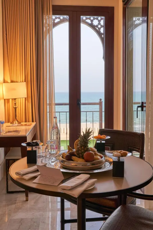 Une table ronde avec des fruits frais est mise en scène dans une chambre donnant sur la mer.