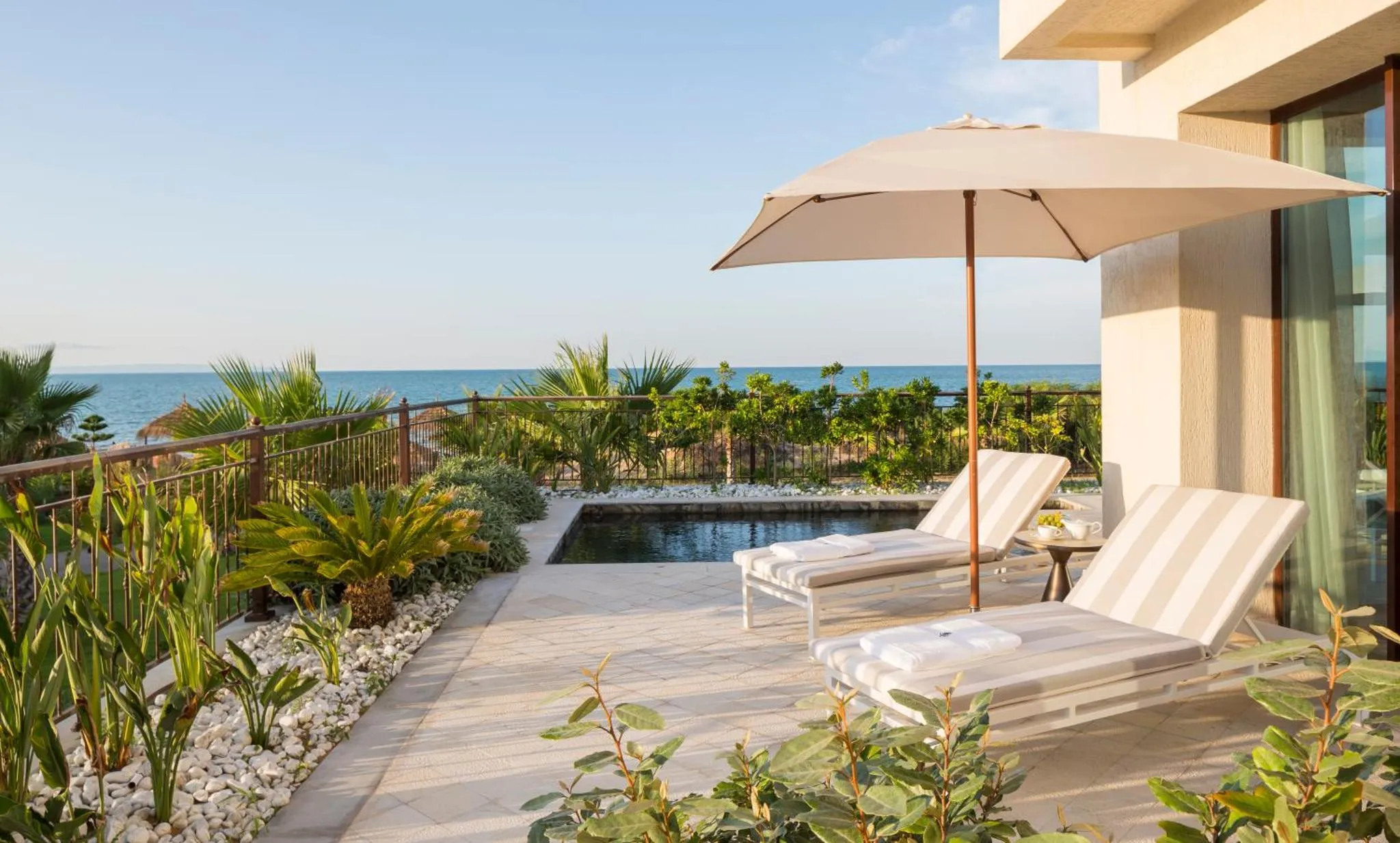 Deux transats invitent à la détente sur une terrasse avec vue sur la mer.