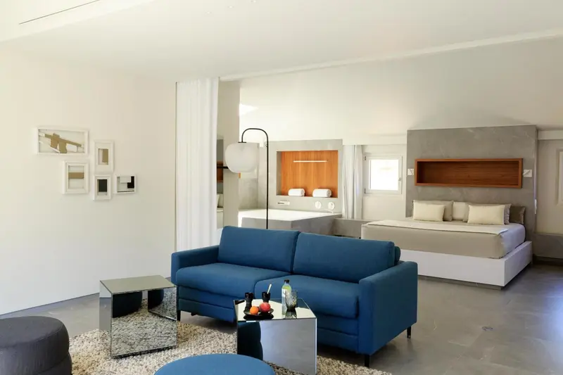 Un espace de séjour lumineux avec un canapé bleu et un lit confortable.
