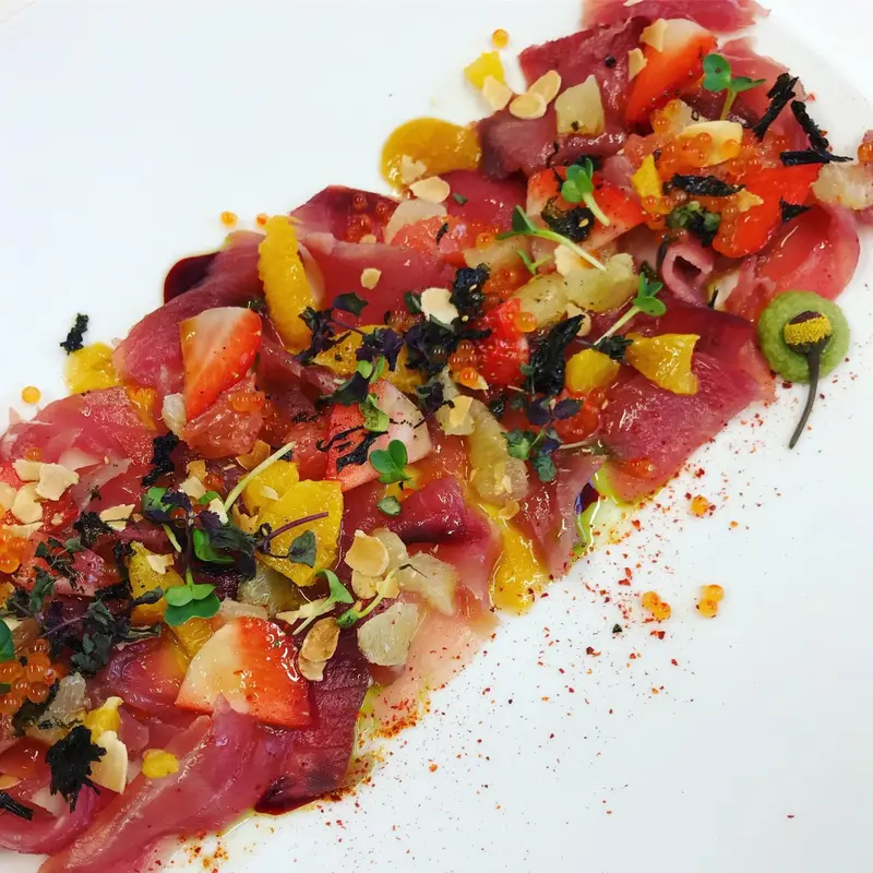 Assiette de poisson cru colorée, décorée de légumes et d'herbes.