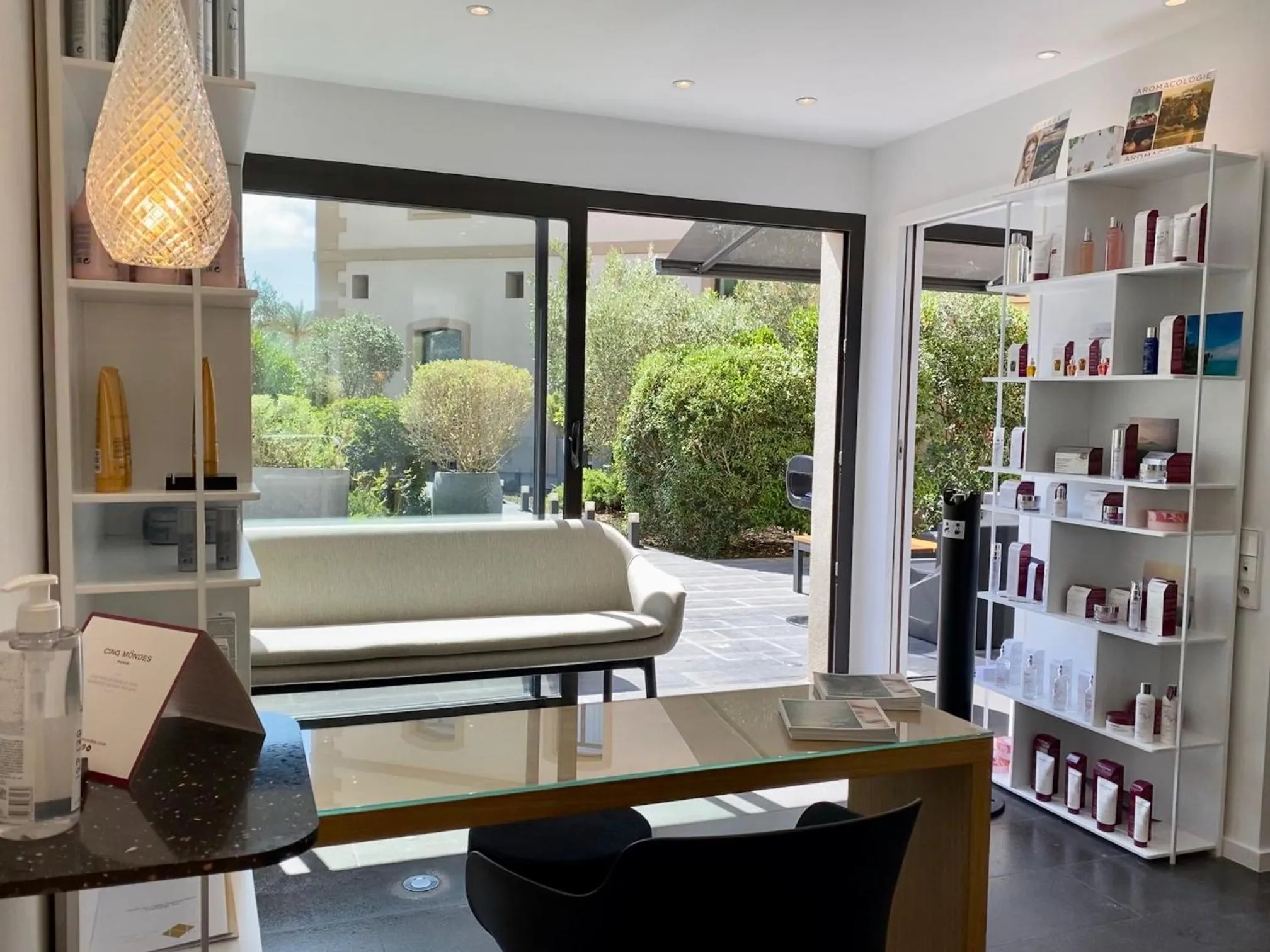 Espace détente lumineux avec canapé blanc et vue sur une terrasse verdoyante.