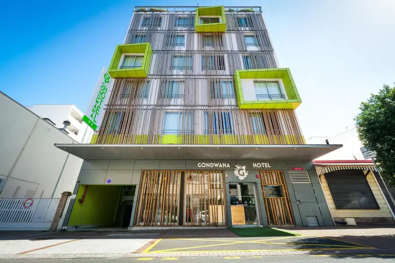 Façade d'un bâtiment moderne avec une entrée et un parking.