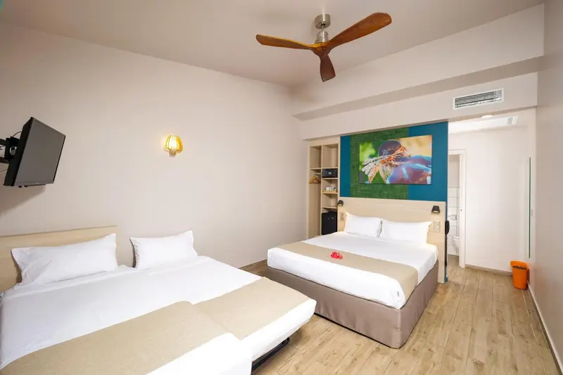 Une chambre lumineuse avec deux lits simples et une décoration murale colorée.