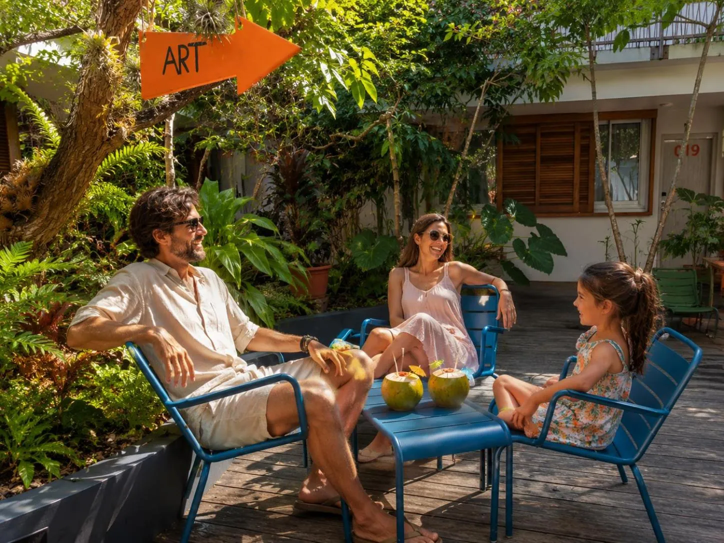 Une famille se détend sur une terrasse en bois avec des boissons tropicales.