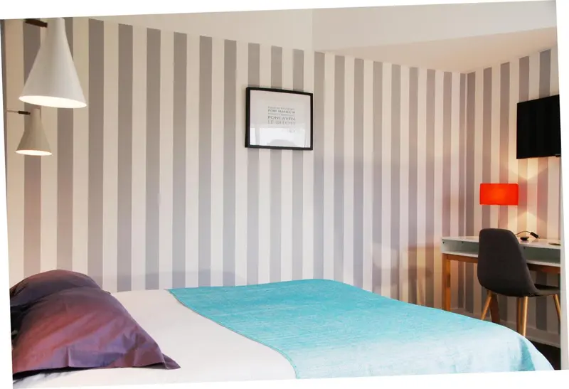 Une chambre avec un lit recouvert d'une couverture turquoise et un bureau.