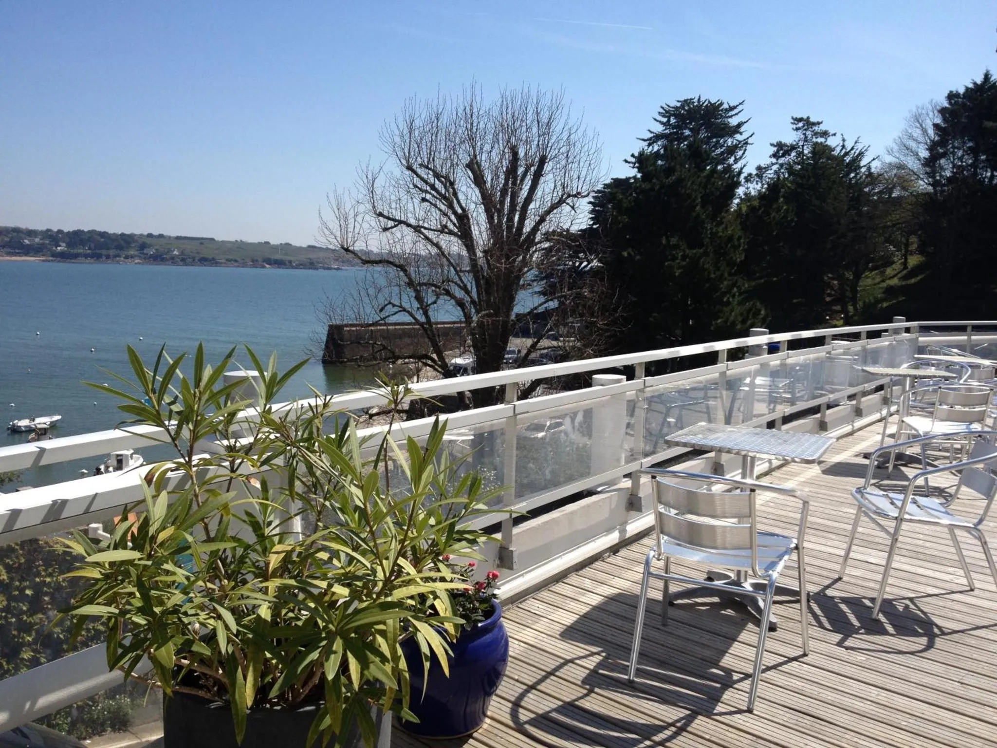 Terrasse ensoleillée avec tables et chaises donnant sur la mer.