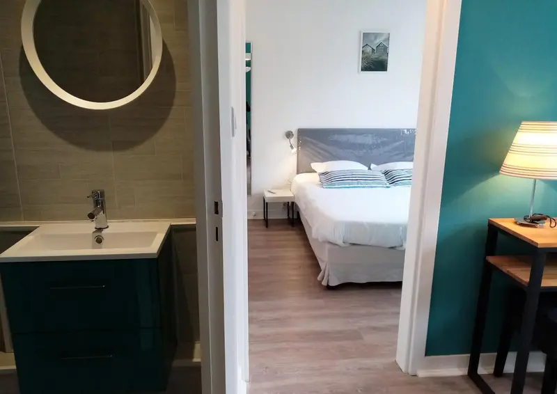 Une chambre lumineuse avec un lit et un coin lavabo.