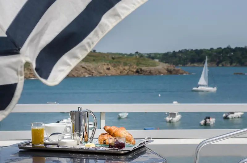 Un petit-déjeuner est servi sur une table avec vue sur la mer et des bateaux.