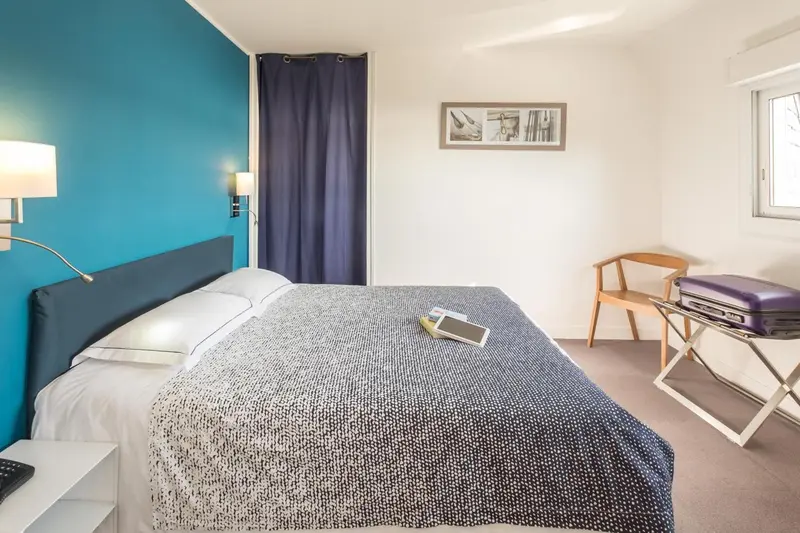 Une chambre lumineuse avec un lit double et un bureau.