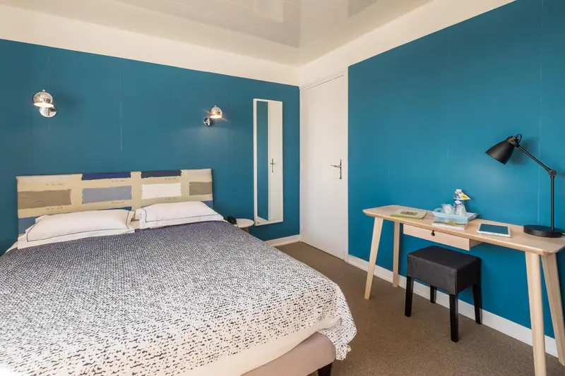 Une chambre lumineuse avec un lit double et un bureau.