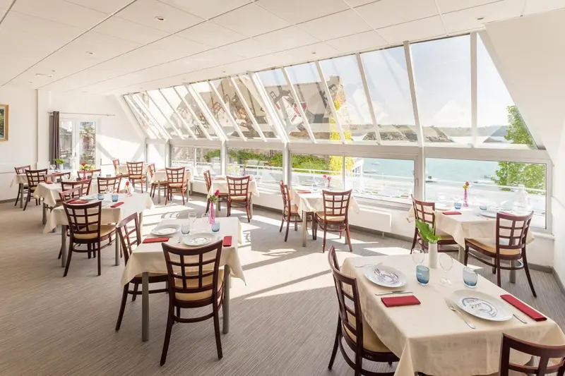 Une salle lumineuse avec des tables dressées pour un repas.
