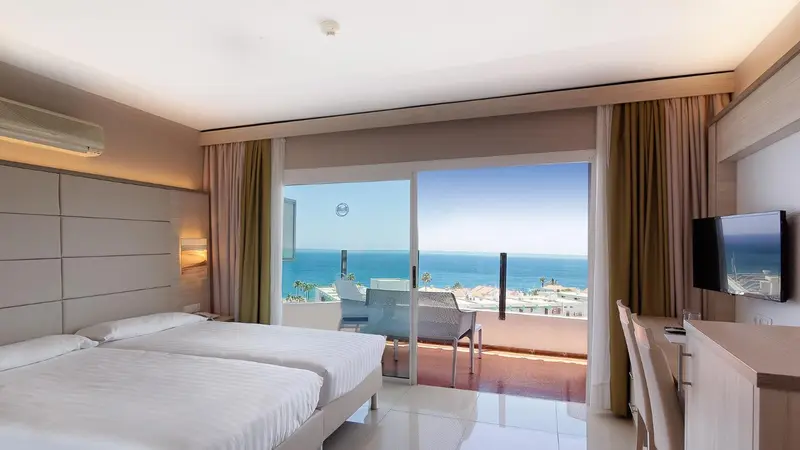 Une chambre lumineuse avec vue sur la mer depuis un balcon.