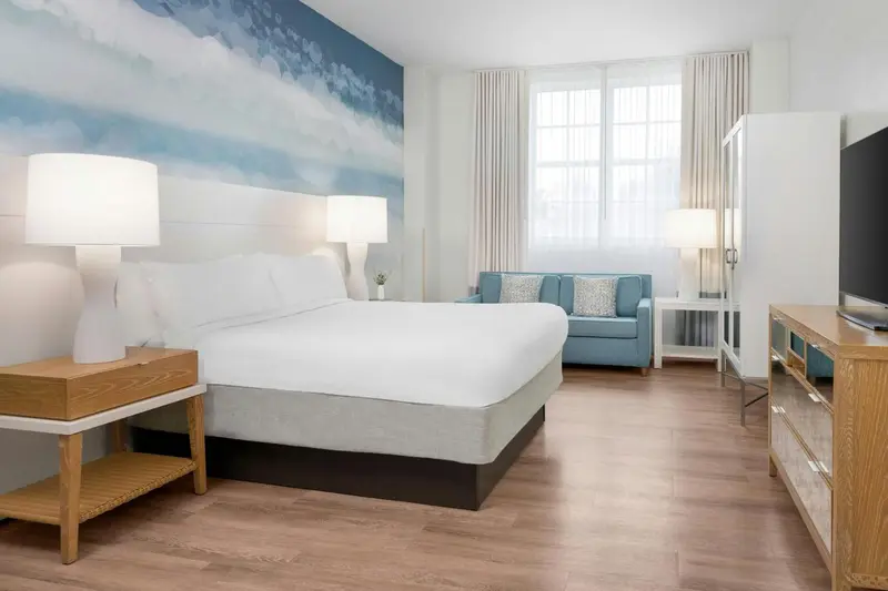 Une chambre lumineuse avec un grand lit et un canapé bleu.