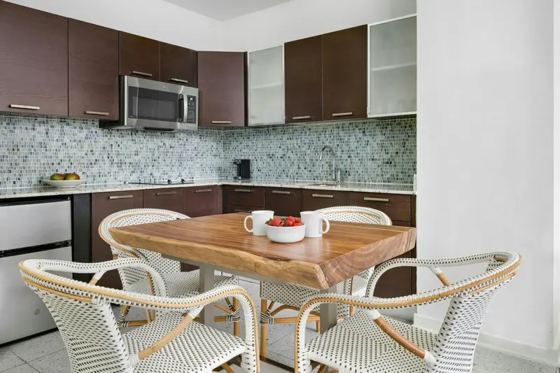 Une table en bois est entourée de chaises en osier dans une cuisine moderne.