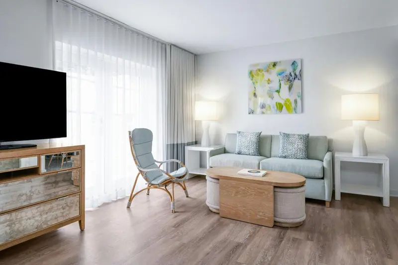 Espace de séjour lumineux avec canapé, fauteuil et télévision.