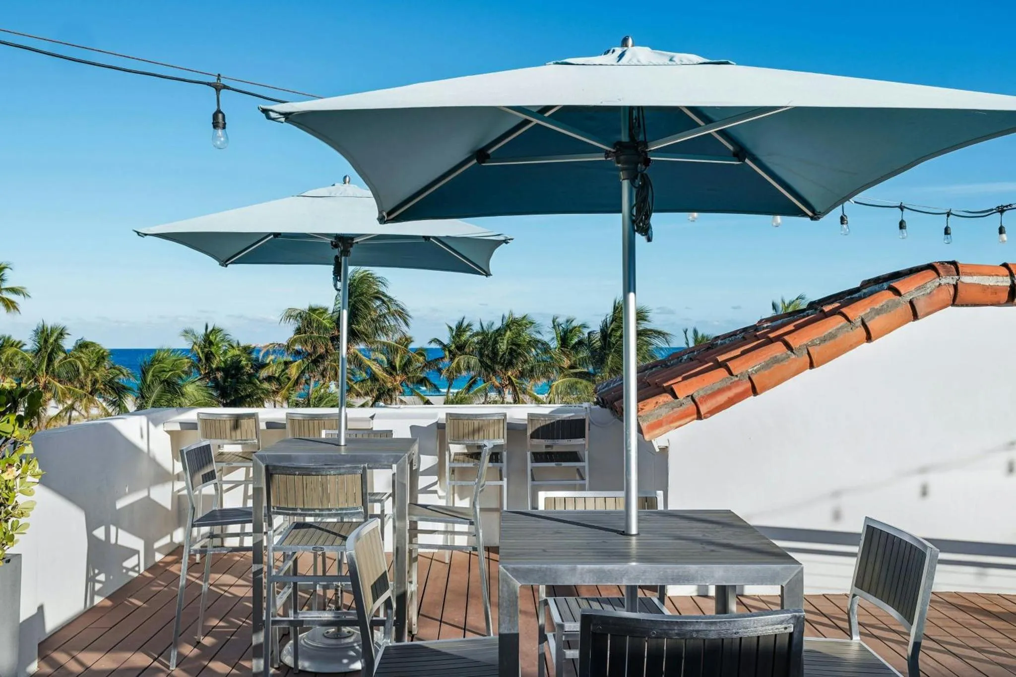 Terrasse ombragée avec tables et chaises donnant sur la mer.