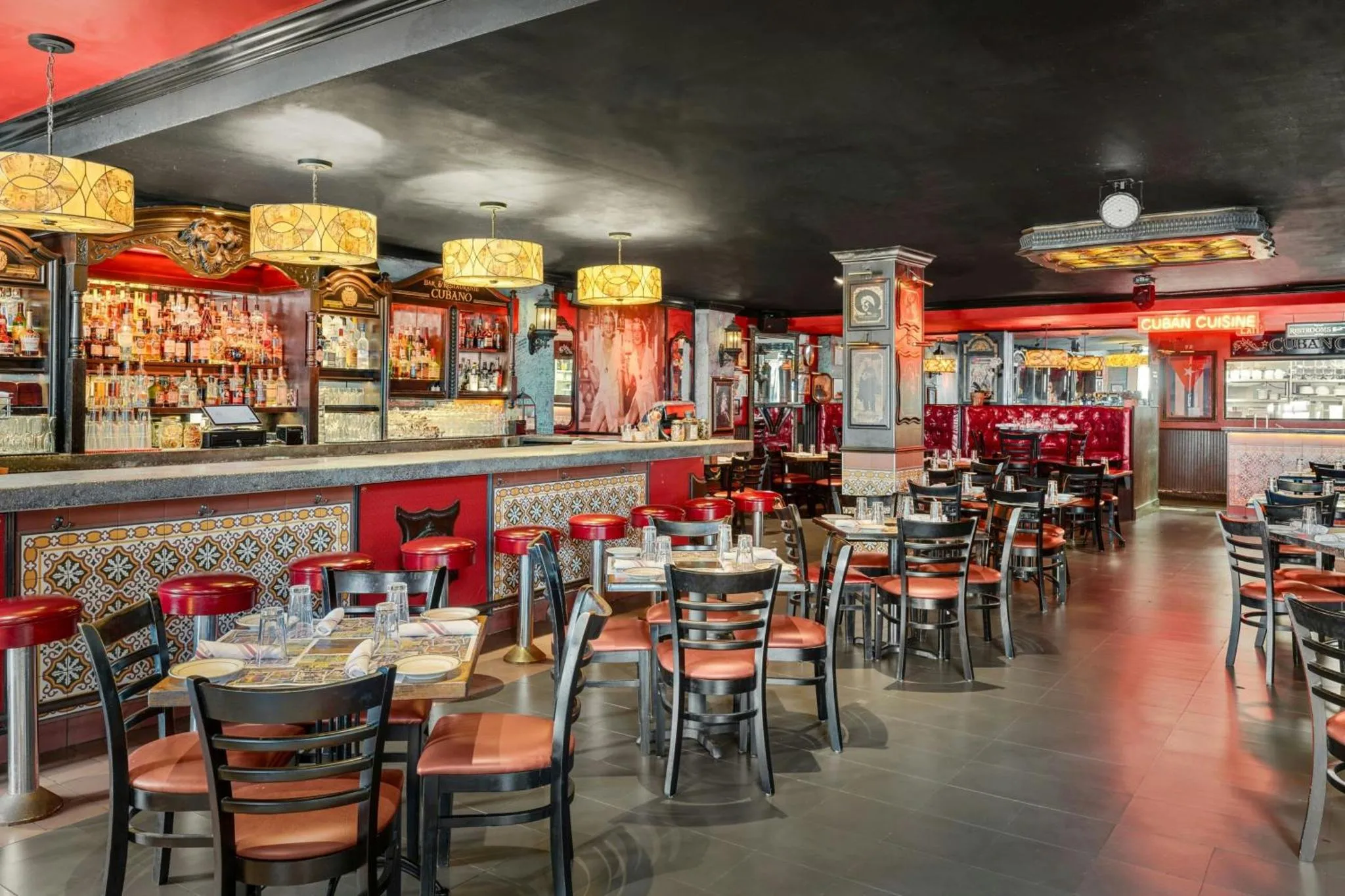 Une salle de restaurant lumineuse avec un comptoir de bar et des tables disposées sur un sol carrelé.
