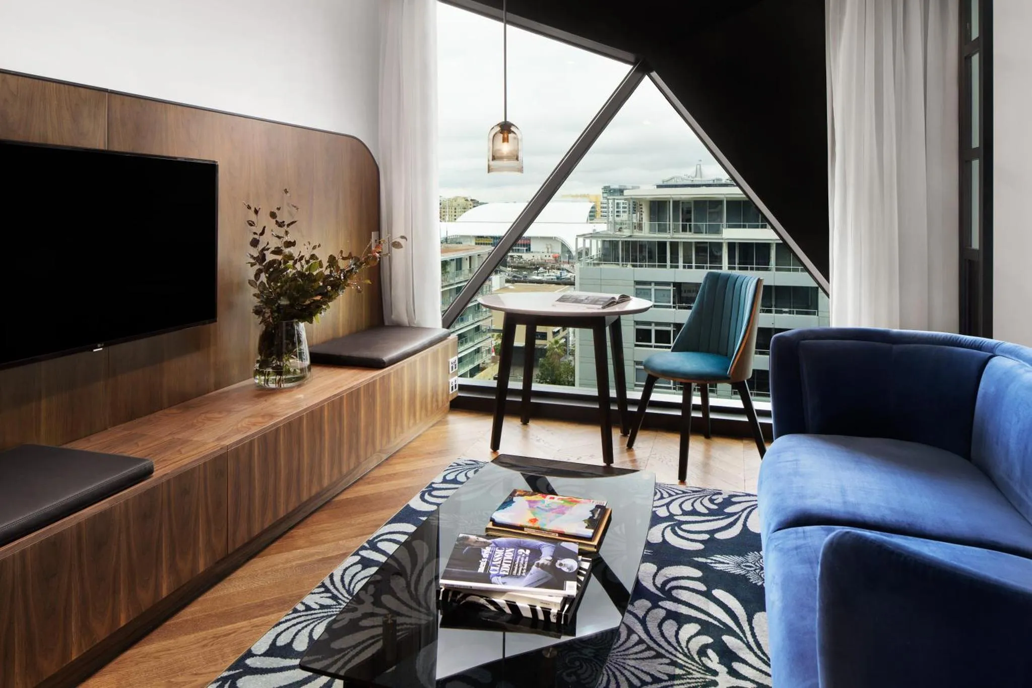 Un salon moderne avec canapé bleu et table basse en verre.