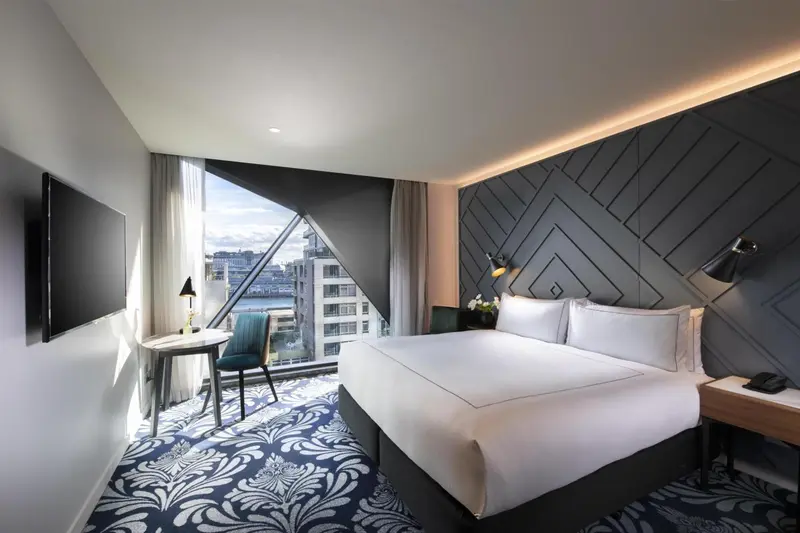 Chambre moderne avec un grand lit et une vue sur la ville.