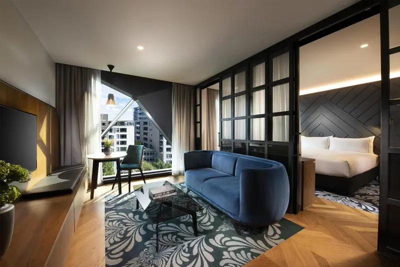 Espace de vie moderne avec canapé bleu et lit confortable.