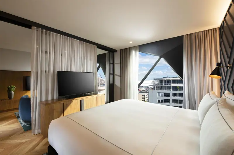 Une chambre lumineuse avec un grand lit et une vue sur la ville.