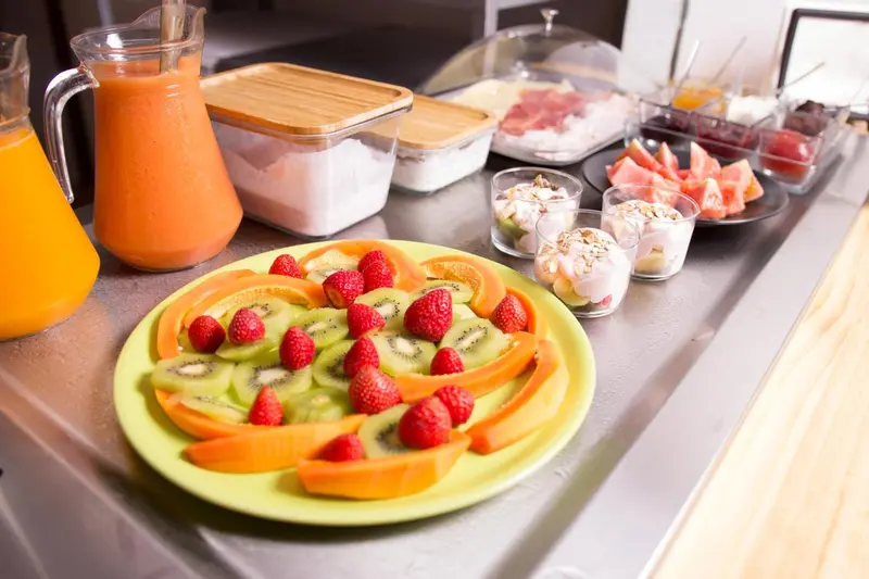 Un buffet propose des fruits frais, des yaourts et des pâtisseries.