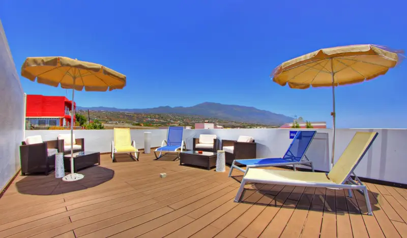 Terrasse aménagée avec des transats et des parasols offrant une vue sur un paysage montagneux.