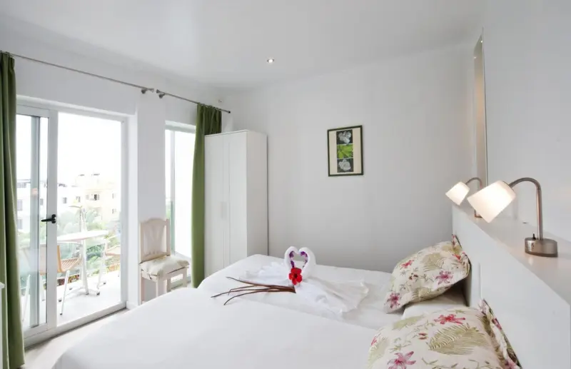 Une chambre lumineuse avec un lit décoré et un accès à un balcon.