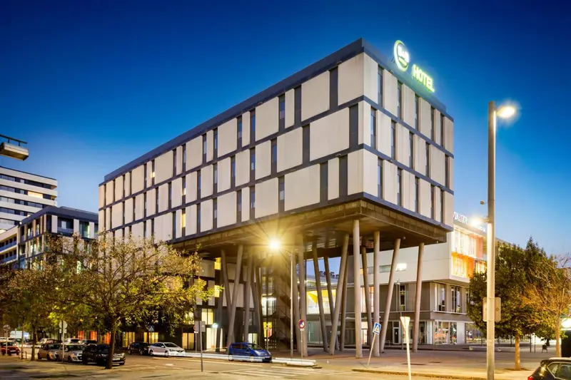 Bâtiment moderne avec une façade lumineuse et un éclairage nocturne.