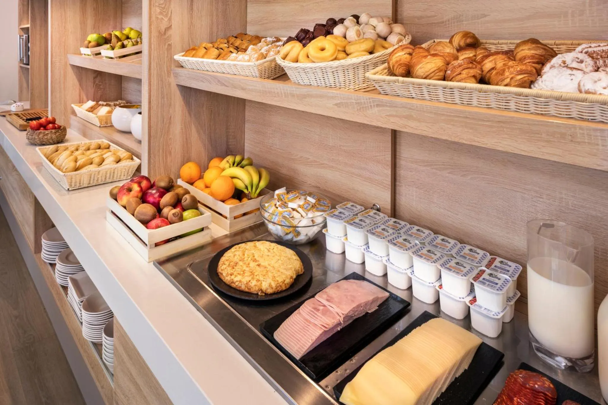 Un buffet propose des viennoiseries, des fruits et des produits laitiers.