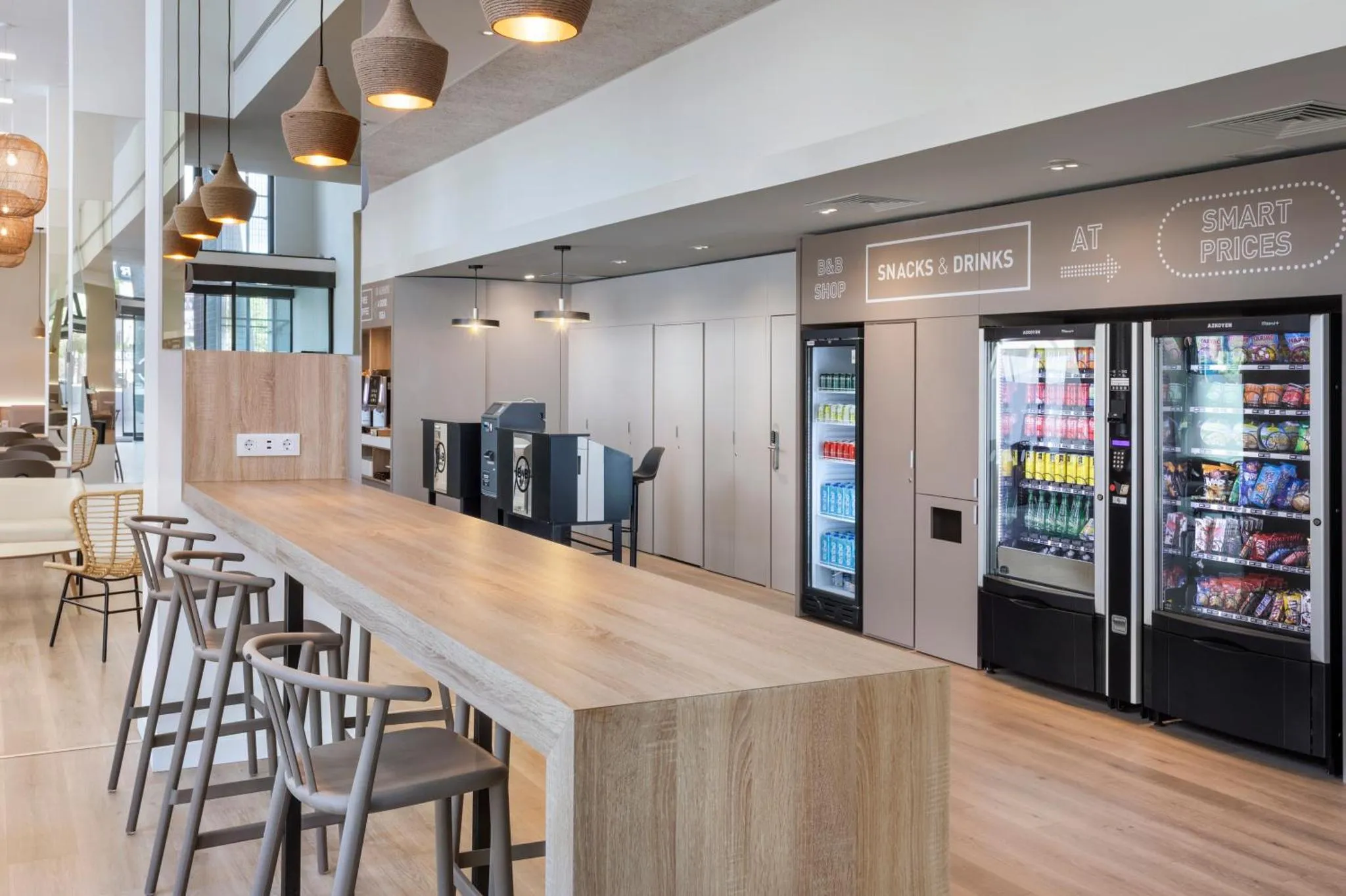Un espace commun lumineux avec un comptoir, des tabourets et des distributeurs automatiques de boissons.