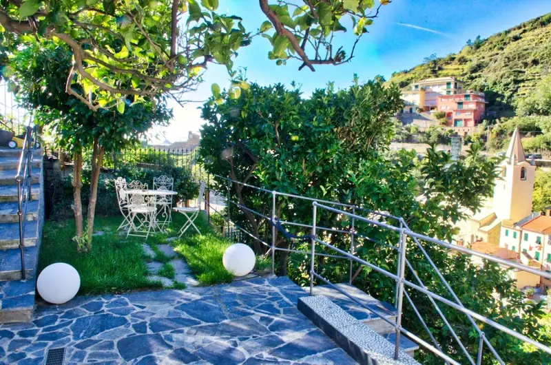 Terrasse pavée avec mobilier de jardin et vue sur un village en pente.