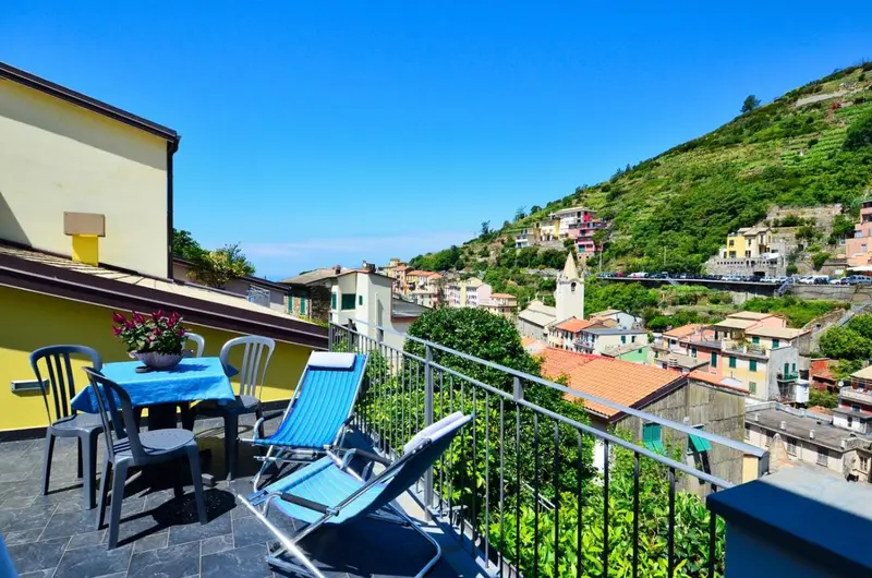 Terrasse avec mobilier de jardin donnant sur un village coloré et la mer.