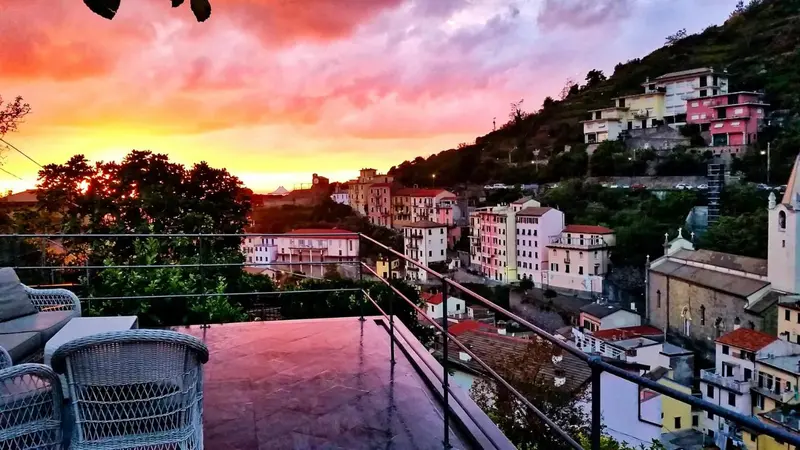 Terrasse avec mobilier d'extérieur donnant sur un village coloré au coucher du soleil.
