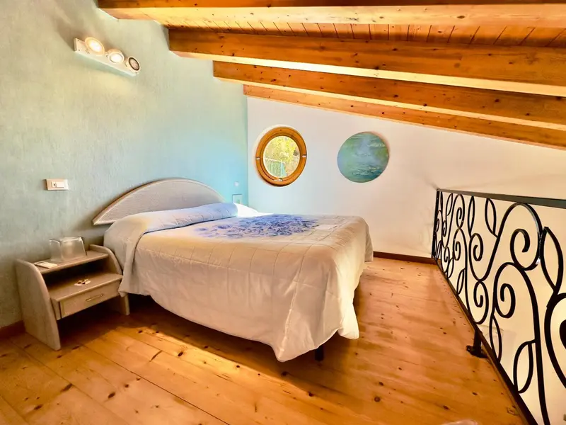 Une chambre lumineuse avec un lit et un parquet en bois.