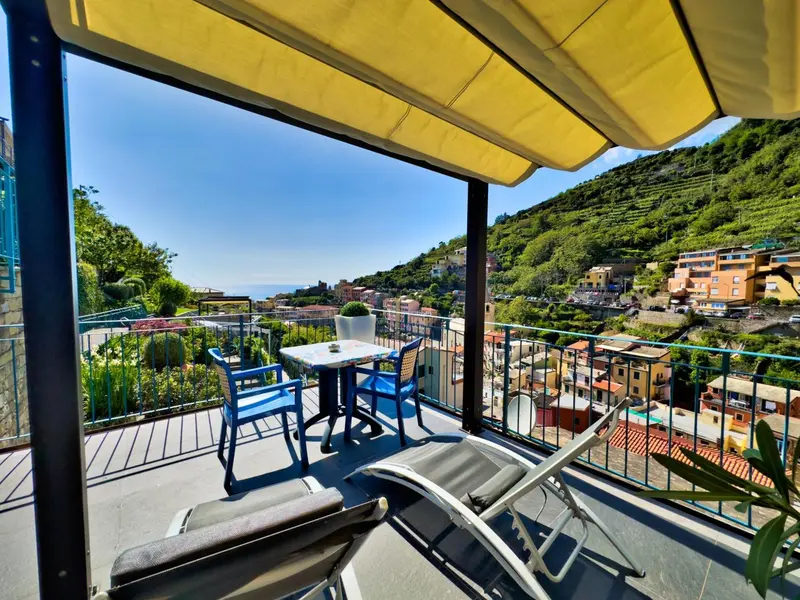 Terrasse avec mobilier de jardin et vue sur un village en bord de mer.
