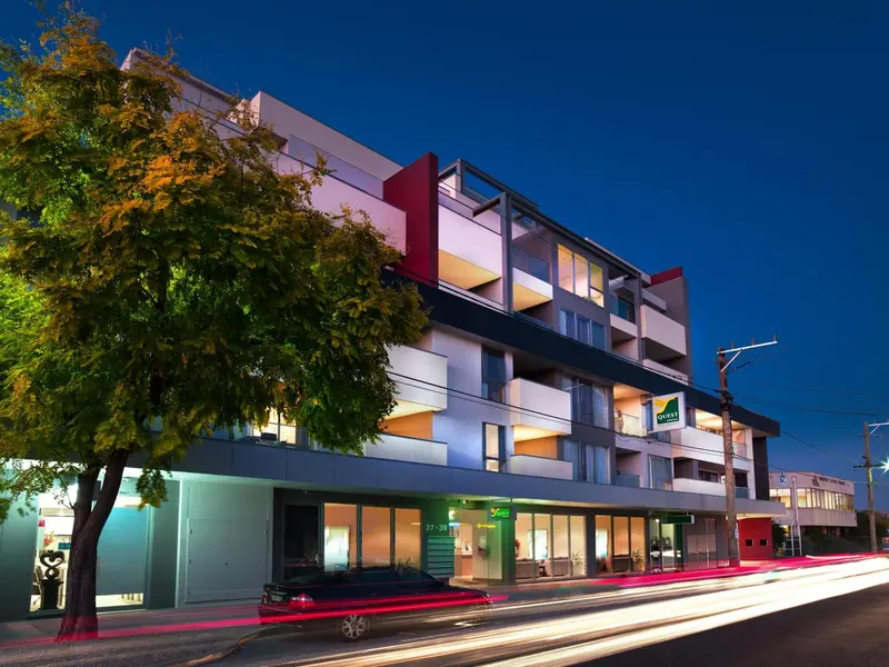 Bâtiment moderne éclairé la nuit avec des voitures passant devant.
